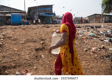 BHIWANDI - INDIA - MAY 15, 2016: A woman carries a water container after filling it from a municipal water tanker in Thane district, Maharashtra.