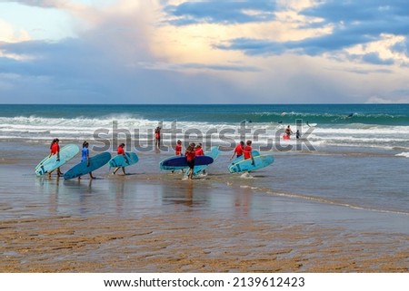 Biarritz, France. Group of young surfers running towards the sea.