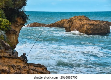 BIARRITZ (FRANCE) October 22, 2021: Older Man Fishing In Rough Sea, On A Summer Day.