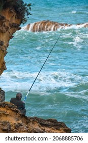 BIARRITZ (FRANCE) October 22, 2021: Older Man Fishing In Rough Sea, On A Summer Day.