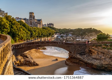 Biarritz, France. Panoramic view of the famous stone bridge to the Rocher du Basta, cityscape and coastline with sand beaches and port for small boats. Golden hour. Holidays in France.