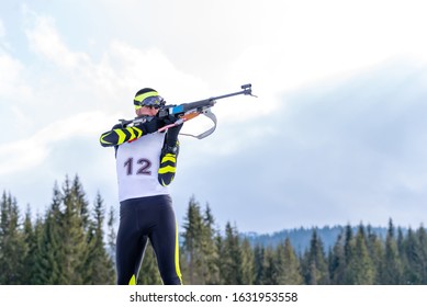 Biathlete holds his breath while shooting the rifle in a standing position during the biathlon race