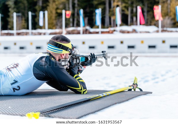 Biathlete shooting with a rifle at a shooting range\
at the race