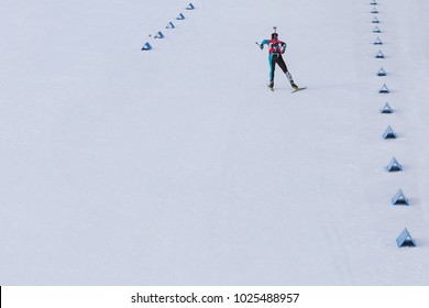 Biathlon racing, biathlete skiing with rifle on his back