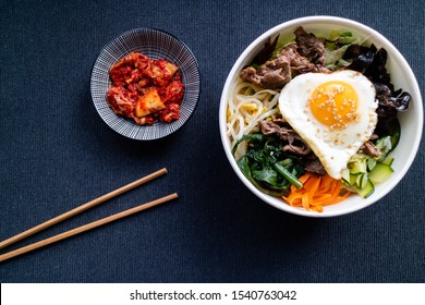 Bibimbap with beef and kimchi on dark background. Korean cuisine.