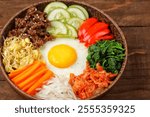 Bibimbap is a Korean dish in the form of a bowl of white rice topped with side dishes of vegetables, beef, eggs and spicy gochujang sauce.