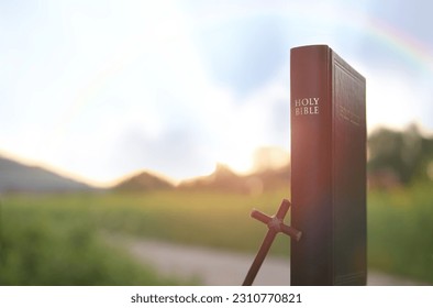 Bible book, sky, rainbow and cross of Jesus Christ and beautiful nature scenery
 - Shutterstock ID 2310770821