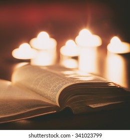 Bible With Candles In The Background. Low Light Scene.