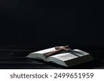 Bible and cross on black wooden table against dark background, space for text. Religion of Christianity