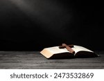 Bible and cross on gray wooden table against dark background, space for text. Religion of Christianity