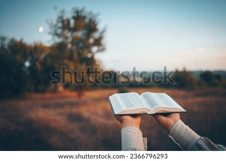 Bible in hands in nature, Christian concept.