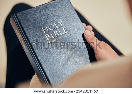 Bible, hands and person in prayer, religion and peace in a lounge, praise and holy worship for guidance. Closeup, believer or faith with meditation, reading book or mindfulness with spiritual or calm