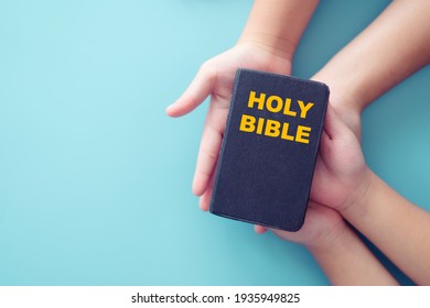 Bible On Kid Hands.Family Christian ,Reading Bible Study.Hands Holding On A Holy Bible.faith, Spirituality And Religion.blue Background.Give Gospel For The Nation.Pray, Trust, Worship, Church, Jesus.