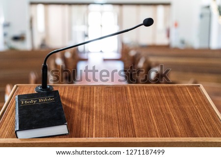 bible on pulpit in church, with light coming in through the front door
