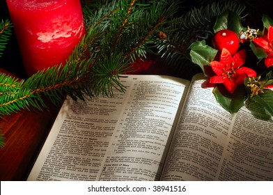 Bible open to the Christmas passage of Luke 2 with evergreen sprigs, candle, and poinsettia decor - Powered by Shutterstock