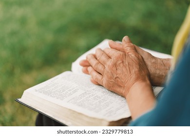 Bible, reading book or old woman praying for hope, help or support in Christianity religion or holy faith. Prayer or senior person studying or worshipping God in spiritual literature at outdoors - Powered by Shutterstock