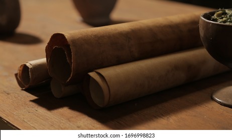 Bible scene: a wooden dining table with scripture scrolls. Close-up of rolls of old paper, cup with food.