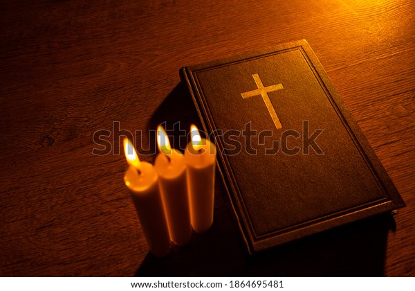 A Bible\
and three burning candles on a wooden table. Christian sermon.\
Christian faith. Protestantism, Catholicism and Orthodoxy. Faith in\
Jesus Christ. Study of the word of\
God.