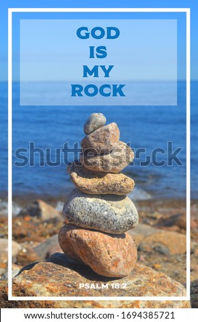 Bible Verse: Psalm 18:2 “God is my rock”  A stack of rocks and stones (cairn) on edge of ocean overlooking the sea with blue sky and ocean in horizon background.