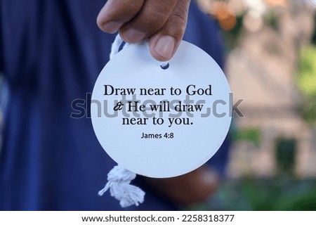 Bible verse quote - Draw near to God and He will draw near to  you. James 4:8 with person showing text on white circle label paper in hand. Christianity concept with bible verses quote.