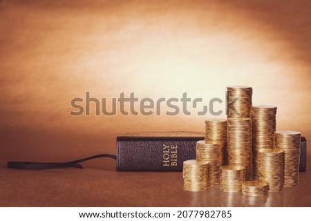 The biblical concept. Golden money on a wooden table with Holy Bible.