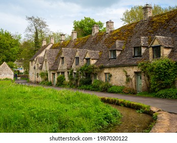 Bibury, Gloucestershire, UK – 5 18 2021: Historic Arlington Row - 17th-century weavers' cottages, in Cotswold stone, beside a water meadow in Bibury village, near Cirencester, in Gloucestershire.