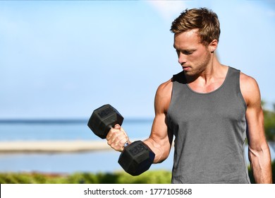 Bicep curl free weights training fitness man outside working out arms lifting dumbbells doing biceps curls. Fit man arm exercise workout exercising arms with dumbbell weight at outdoor beach gym.