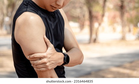 Bicep tendonitis or front arm muscle inflammation. Asian athlete man suffering from upper arm pain while doing outdoor exercise in the park. Sport injury concept
