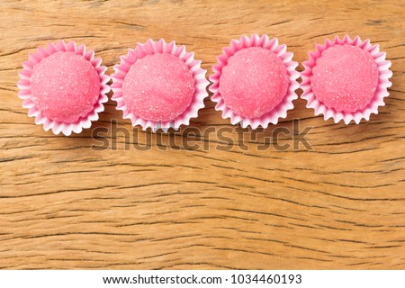 Bicho de pe is a strawberry flovoured brazilian candy. Common in children birthday parties sweet. Overhead of candy ball on rustic wood table.