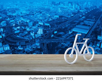 Bicycle 3d Icon On Wooden Table Over Modern City Tower, Street, Expressway And Skyscraper, Business Bicycle Service Concept