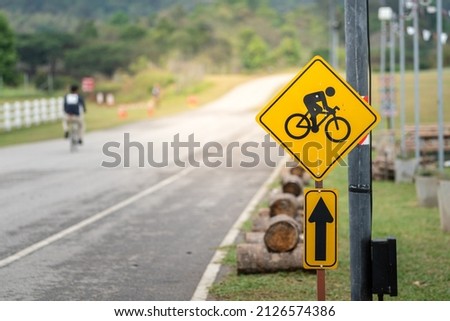 Bicycle or Bike lane traffic icon symbol with a people riding as blurred background. Sign and symbol for sport and recreation activity.