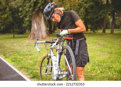 Bicycle brake on the ride. Sporty Senior Woman cyclist fixing her bike brakes outdoor - Powered by Shutterstock