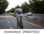 bicycle courier rides on a bike path in the city, wearing a helmet and carrying a small delivery bag