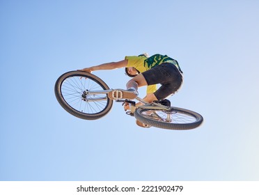 Bicycle, cyclist man and jump of adrenaline junkie from below riding in a competition with copyspace. Extreme sport, bicycle and cycling man stunt while on bike against a blue sky background - Shutterstock ID 2221902479