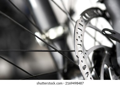 Bicycle disk brakes close up, grey metal disc attached to bike wheel, effective popular mountain bicycle brakes. Hydraulic disk brakes on bicycle wheel, bicycle spokes gray background