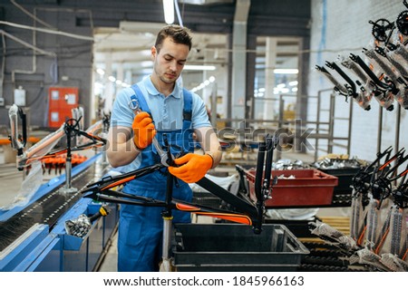 Bicycle factory, worker holds teen bike frame