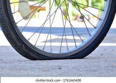 A bicycle with a flat wheel or tire, damaged tire parked by the roadside. Deflated rubber and exposed inner tube signal a sudden halt to the ride, it awaits to repair. - Powered by Shutterstock