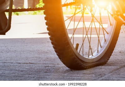 A bicycle with a flat wheel or tire, damaged tire parked by the roadside. Deflated rubber and exposed inner tube signal a sudden halt to the ride, it awaits to repair. - Powered by Shutterstock