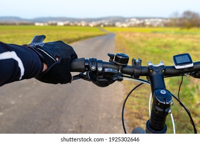 A Bicycle Handlebar Seen From The First Person Perspective And With A Mans Hand On The Handle. Visible Bike Computer And Bell.