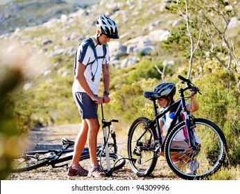 Bicycle Has Flat Tyre And Man Helps His Girlfriend Pump It Up. Outdoors Mountain Bike Couple.