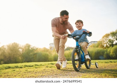 Bicycle, having fun. Happy father with son are on the field at summertime. - Powered by Shutterstock