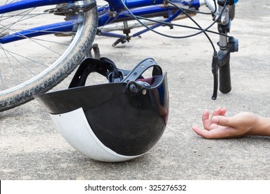 bicycle and a helmet lying on the road with hand of human, accident concept