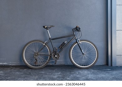 Bicycle leaning against a gray wall with copy space. Side view.
