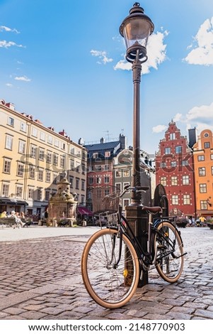 Bicycle leaning against a lamppost in Stockholm Gamla Stan. Bike parked in a cobbled square in Stockholm old town. Illustration of Swedish lifestyle or Scandinavian preferred transportation vehicle