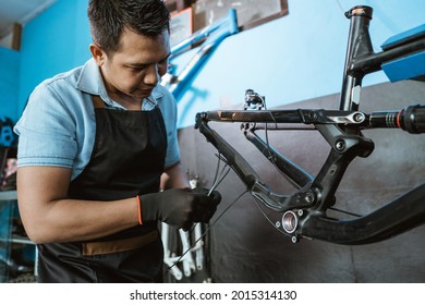 A Bicycle Mechanic Attaches Brake Cables While Assembling A Bicycle Frame In A Repair Shop