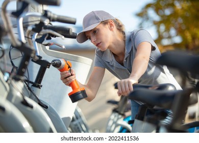 Bicycle Mechanic Using A Drill On A Bike Outdoors