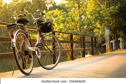 Ein Fahrrad auf einer Brücke mit Sonnenlicht und grünem Baum im Park im Freien für Hintergrund