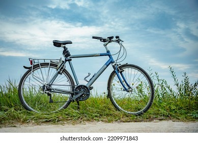 Bicycle on the edge of a field without a cyclist on green grass on the side of the road in summer time with blue sky and clouds - Powered by Shutterstock