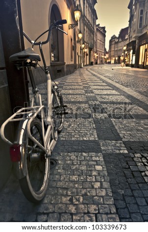 Bicycle on an empty alley with lanterns in Prague at dawn