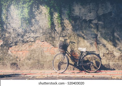 Bicycle on roadside with peeling brick wall background. Bicycle in front of brick wall. Toned image.